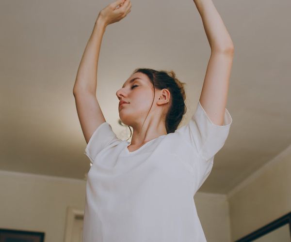 Person stretching peacefully in a bright room with plants.